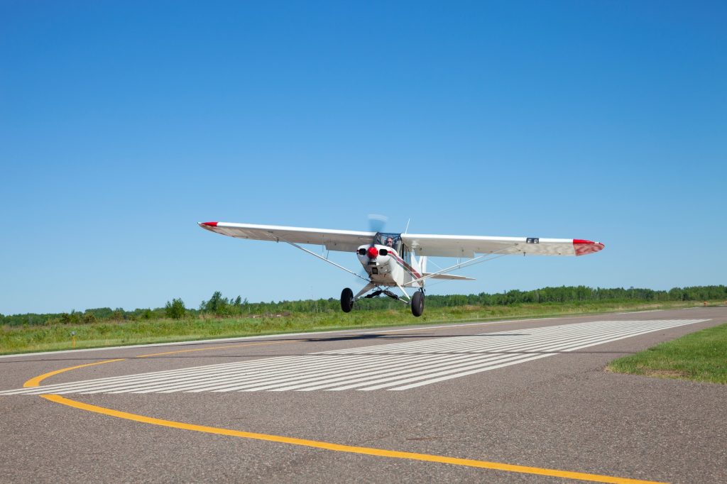 Small single engine airplane takes off from a municipal airfield in rural Minnesota